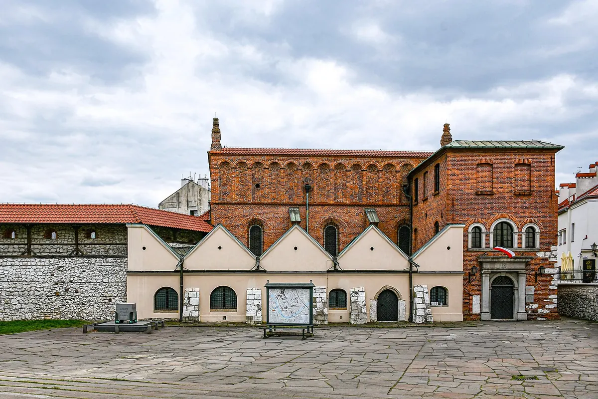 Stara Synagoga na Kazimierzu – ceglany budynek z dachówkowym dachem i rzędem łukowych okien, widoczny zza brukowanego placu.