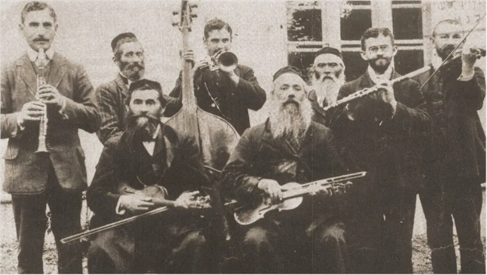 갈리치아의 로하틴 출신 한 가족 클레즈머 악단을 담은 1912년 사진: 수염을 기르고 검은 재킷을 입은 남성들이 클라리넷, 플루트, 바이올린, 더블 베이스, 금관 악기를 들고 있다.